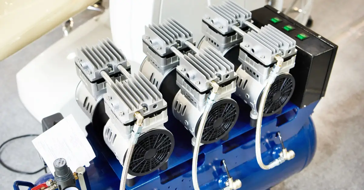 USAirCompressor-366212-Air-Compressor-Dentist-image-a1 - Compresseur d'air américain A blue air compressor on wheels with machines attached to the top sitting next to a chair in a dentist’s office.