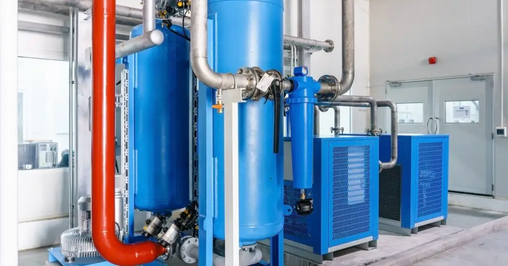 Two light blue air compressors and refrigerated air dryers with a red pipe coming out of them. - US Air Compressor Two light blue air compressors and refrigerated air dryers with a red pipe coming out of them.
