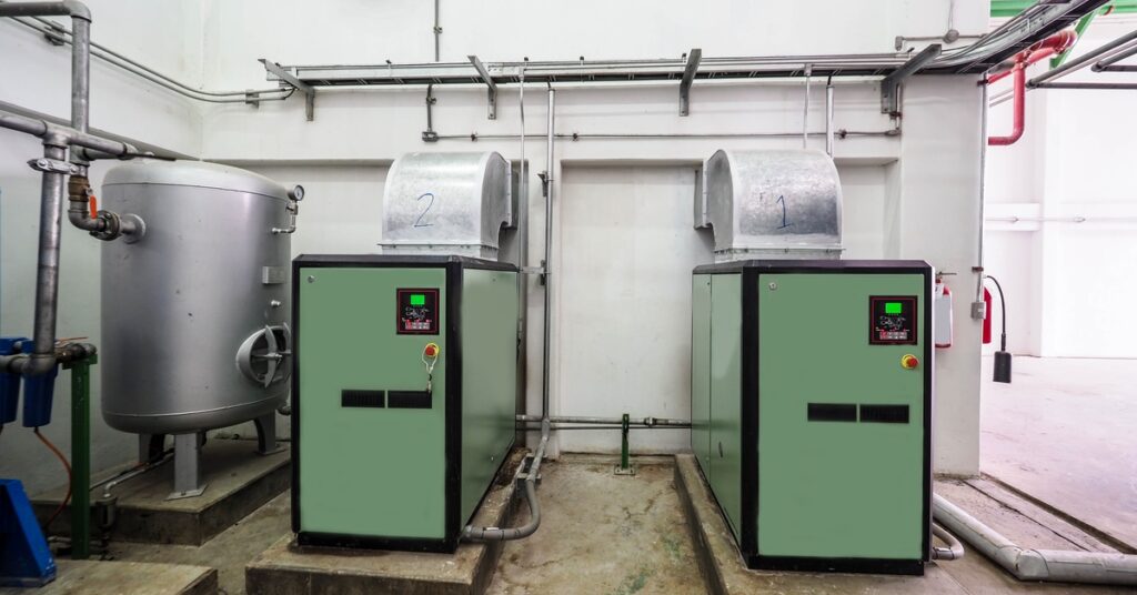 Two green and black refrigerated air compressor units with HVAC pipes coming out of them, and labeled “1” and “2.”
