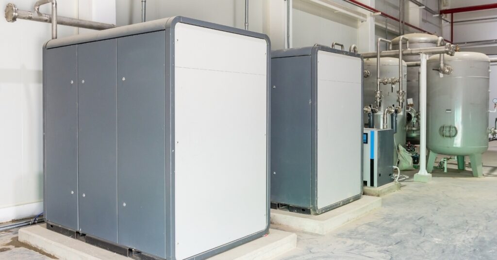 A gray and white industrial air compressor system with large machinery and metal pipes between units.