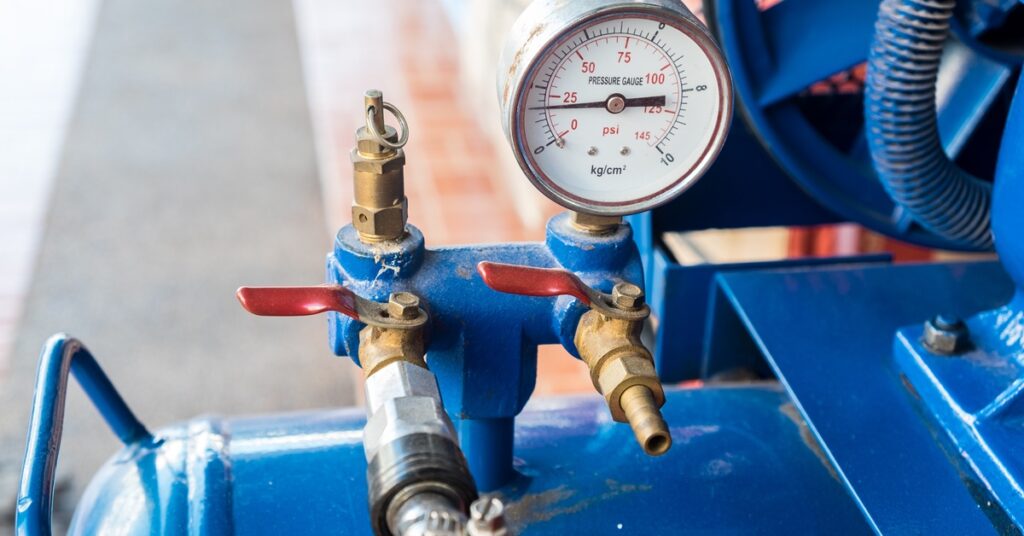 A close-up view of a blue air compressor tank's pressure gauge, which is reading a pressure of approximately 19 psi.